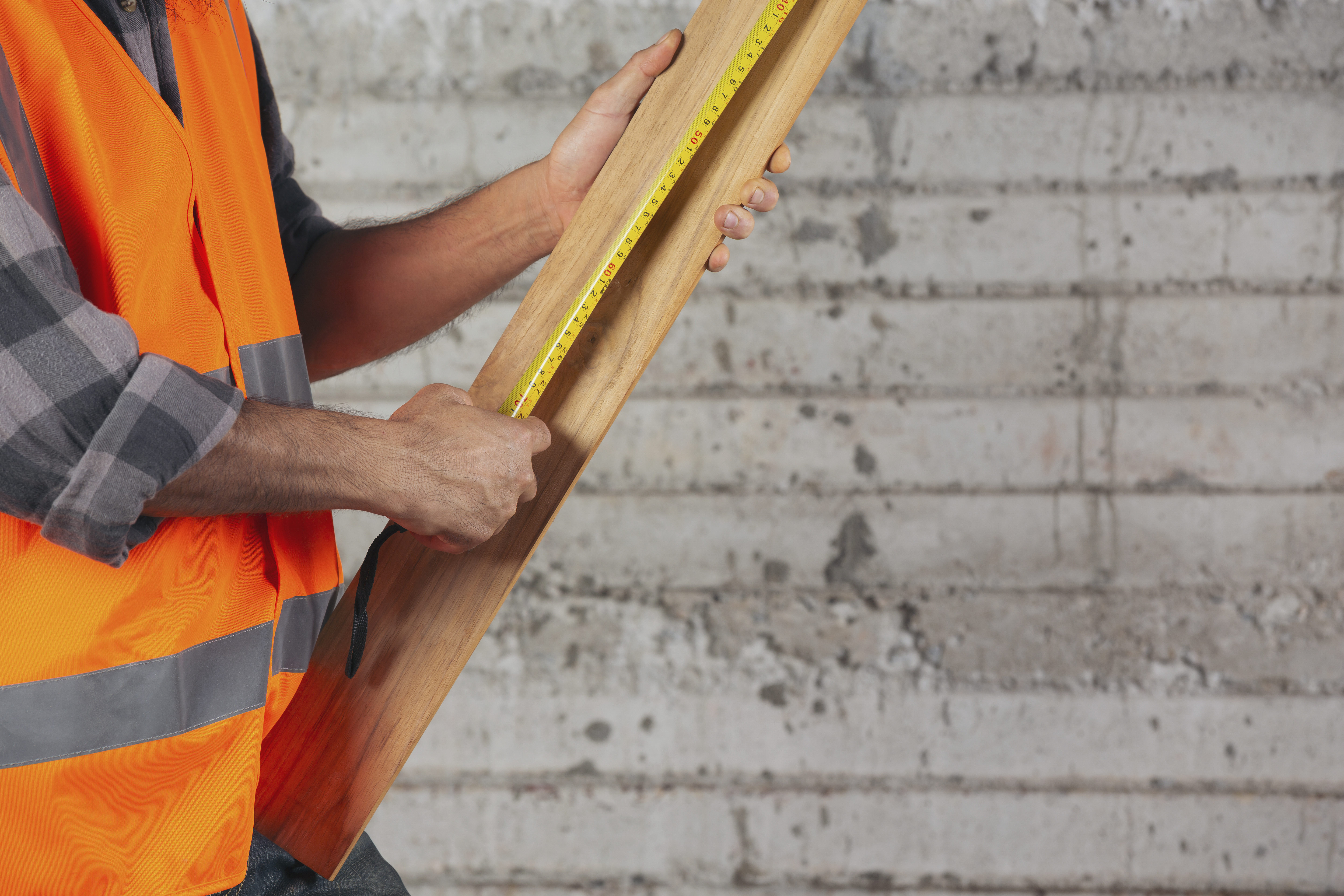 Worker measuring a piece of wood with a tape measure